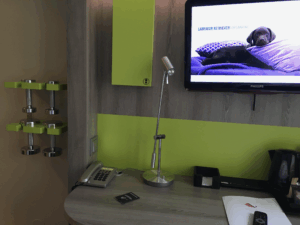 ストックホルムのProfilHotels Central客室内、北欧デザインのデスク周辺に備え付けられたダンベルとテレビ
