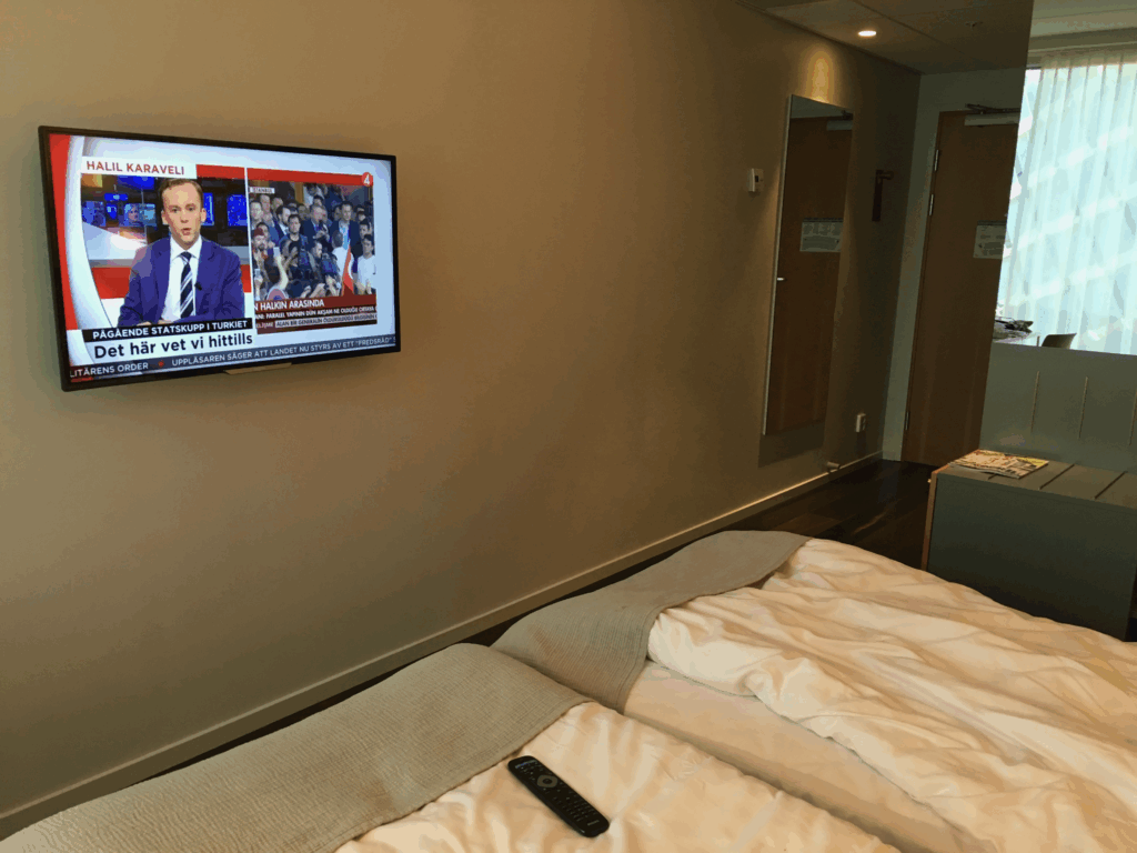 客室のテレビとベッド。壁掛けテレビでニュースを視聴できる。窓際には自然光が差し込み、明るい空間に。