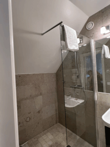 Hotell Slottsbackenのシャワールーム。清潔感のあるタイル張りの壁とガラス仕切りが特徴的なバスエリア。