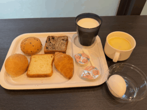 JRイン札幌の無料朝食。パン数種とゆで卵、コーンスープ、牛乳が揃ったシンプルながら満足感のある内容。