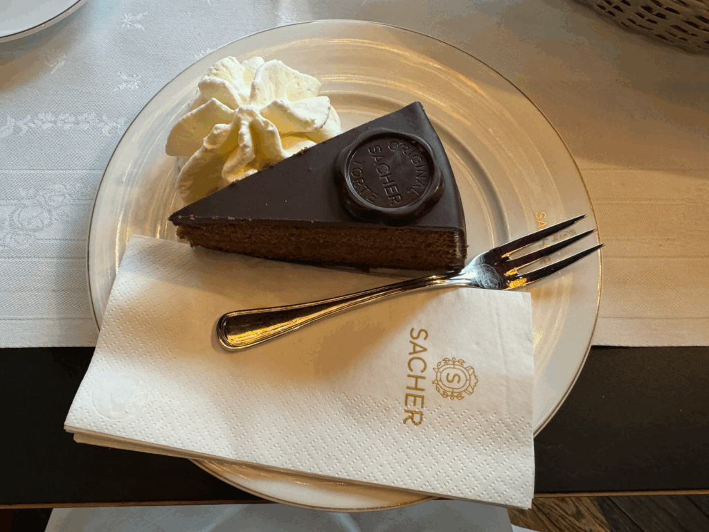 白い皿に載せられたザッハトルテとホイップクリーム(Sacher-Torte served with whipped cream on a white plate)