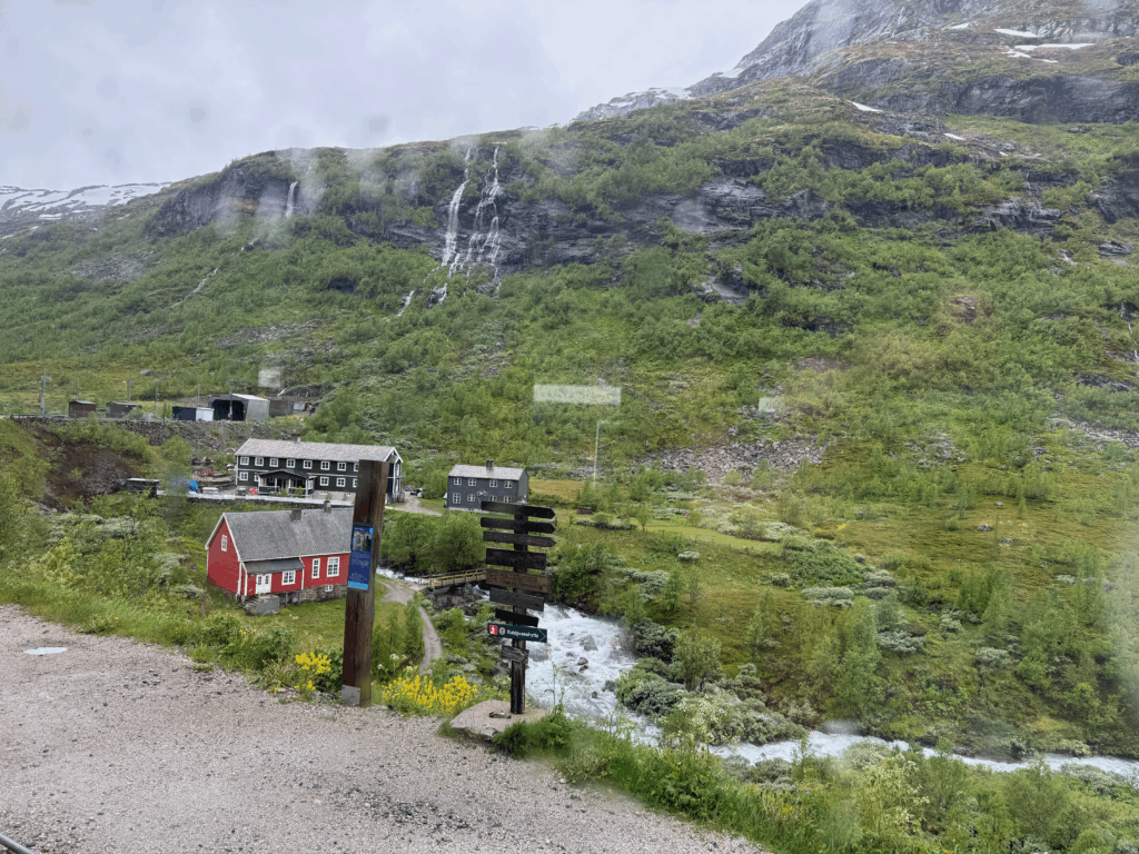 フロム鉄道の車窓から見えるミルダール周辺の風景。赤い家と滝がある山間の景色