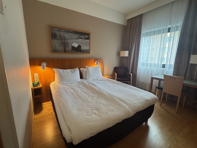 ホリデイ イン ヘルシンキ-ヴァンター エアポートのクイーンベッド周り。ヘッドボード照明と落ち着いた内装。