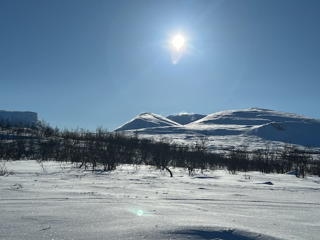 スウェーデン・アビスコの雪原と青空に輝く太陽の逆光写真