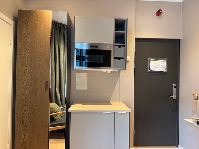 部屋備え付けの電子レンジと収納キャビネット。玄関横のコンパクトな設備