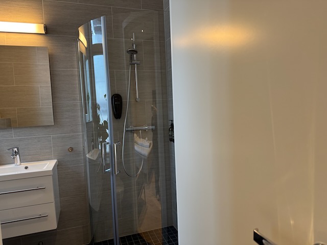 清潔なタイル張りのバスルームとガラスドアのシャワーブース