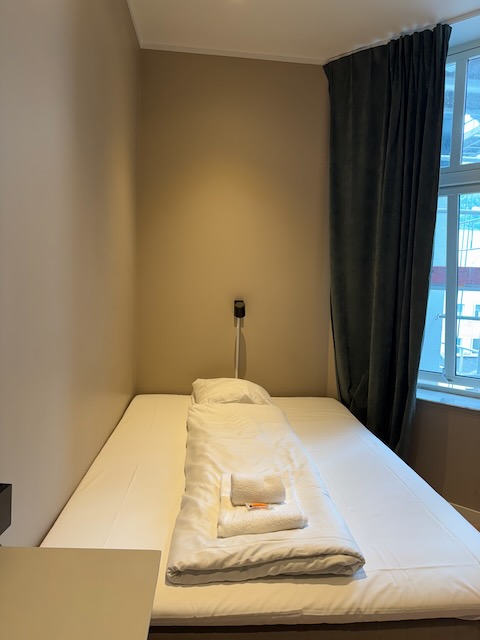 ベルゲンのAirbnb客室。窓際に設置された清潔なベッドと落ち着いたベージュの壁