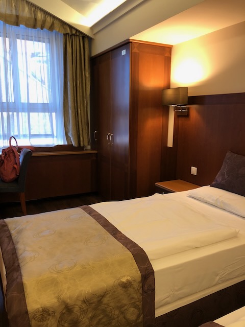 木製の大きなクローゼットがあるツインルーム。暖色系の照明で落ち着いた雰囲気のインテリア