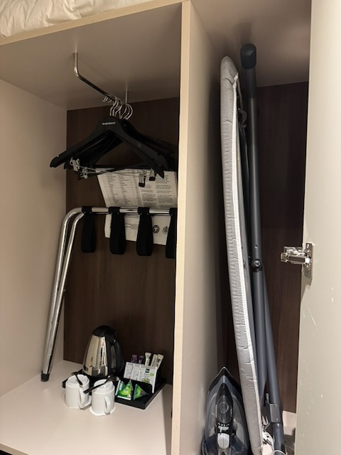Clarion Hotel Arlanda Airport Terminal客室のクローゼットに収納されたアイロン台とハンガー
